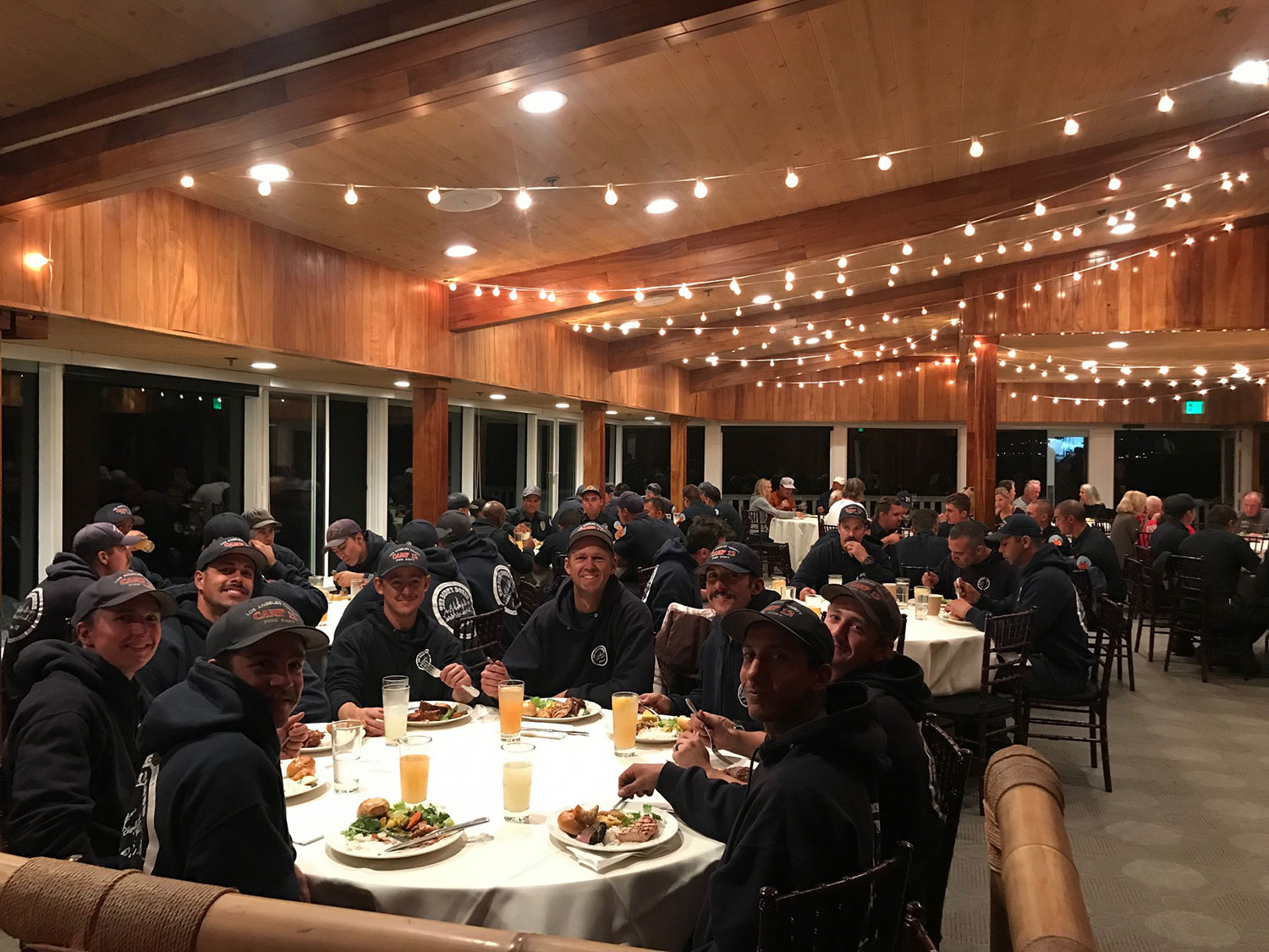 Group of firemen eating dinner in large open indoor room