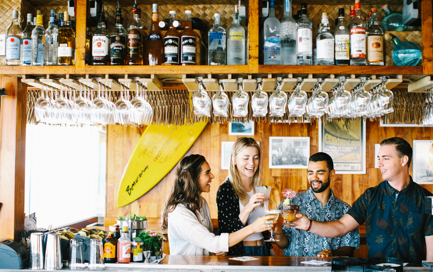 four people at a bar cheers-ing