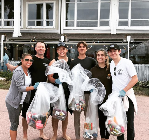 People posing for a photo after picking trash up on a beach